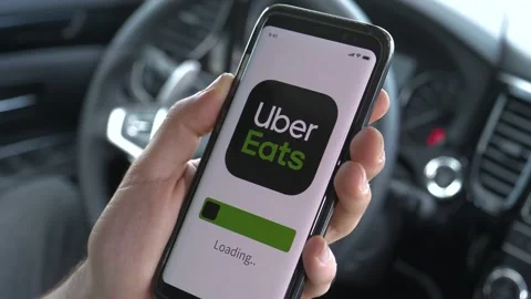 Driver Loading Uber Eats Ride Sharing App on a Smartphone Inside a Car Stock Footage 132598191