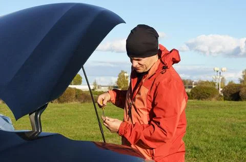 The driver looks at the dipstick to check the engine oil level. Stock Photos