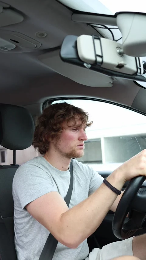 Driver looks sleepy and low on energy while continuing to drive through the city Stock Footage 342923821