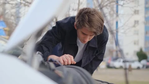 A driver looks under the hood of a broken car trying to figure out what's wrong Stock Footage 304007175
