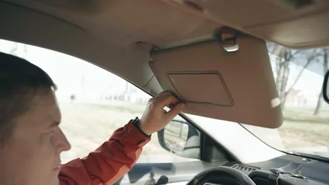 The driver lowers the sun visor while driving. Stock Footage 220642928