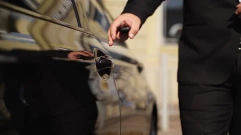 Driver man in black suit opens car door handle. Businessman gets in in a vehicle Stock Footage 199290898