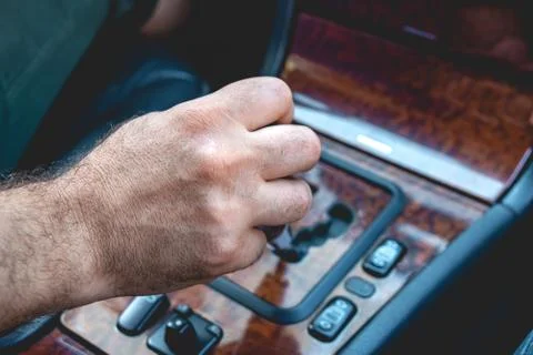 Driver man hand holding automatic transmission in car. Male hand changing lev Stock Photos