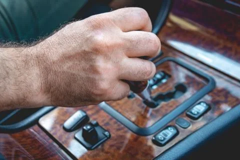 Driver man hand holding automatic transmission in car. Male hand changing lev Stock Photos