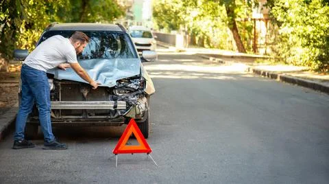 Driver man looking on wrecked car in car accident. Man regrets about fixing car Stock Photos
