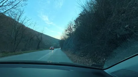 Driver moves slowly along forested mountain road Видео 331063188