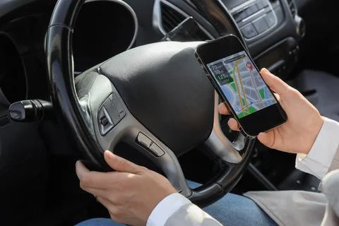 Driver navigating with smartphone GPS application, modern car interior, digit 库存照片