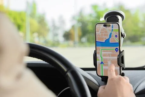 Driver navigating with smartphone GPS map displayed on dashboard mount, moder Stock Photos