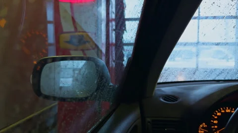 Driver observes rain. Neon lights and water drops create cinematic mirror effect Stock Footage 328735563