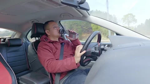 A driver opens a bottle and drinks while driving. Stock Footage 329164381