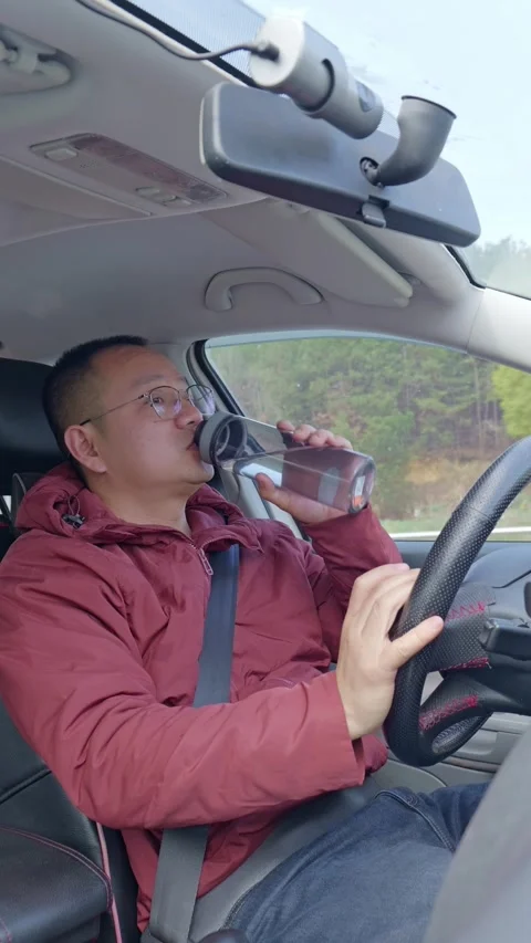 A driver opens a bottle and drinks while driving. Stock Footage 329167808