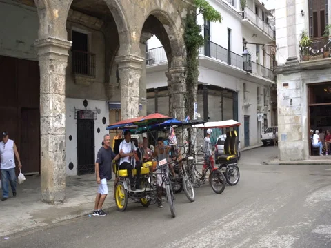 Driver with passenger leave parking zone on local taxi trishaw. Area next to Stock-Footage 70918033