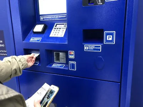 A driver paying parking fee in pay station, ATM paid parking, using smartphone Stock Photos