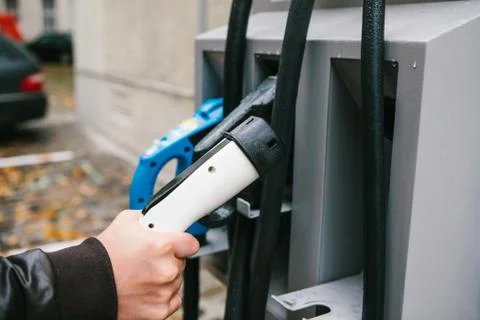The driver picks up a cable to charge the electric vehicle. A modern and eco Stock Photos