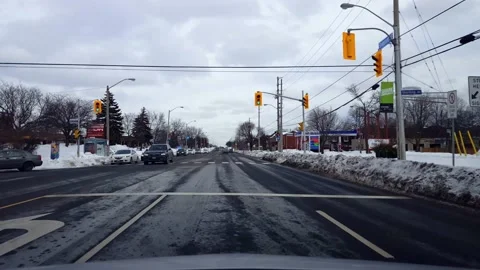 Driver Point of View Driving City Street Along Businesses and Traffic in Winter Stock Footage 169171572