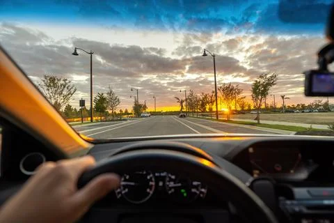 Driver point of view on Florida city street at sunset with hands on steering  Stock Photos