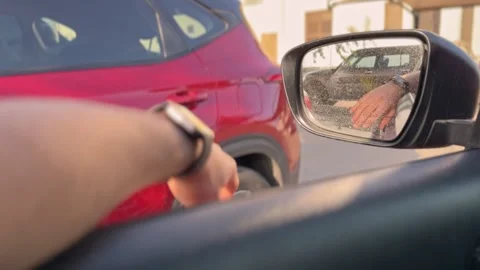 Driver Pointing at Red SUV Beside Car with Side Mirror Reflection in Parking Lot Stock-Footage 332381380
