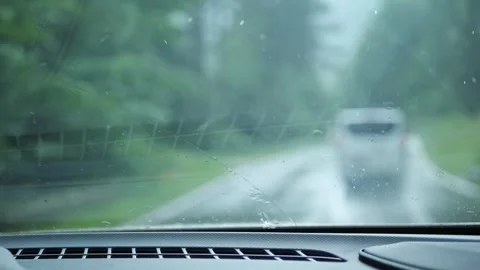 Driver POV through rainy windshield following a van on a wet forest road Stock Footage 341700091