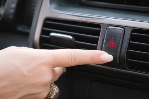 Driver presses his finger on the button to turn on the emergency stop signal Stock Photos