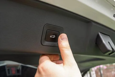 Driver presses power tailgate button inside car trunk, showing modern cargo Fotos de archivo