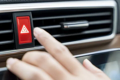 The driver is pressing the emergency stop button on the car dashboard. whil.. Stock Photos