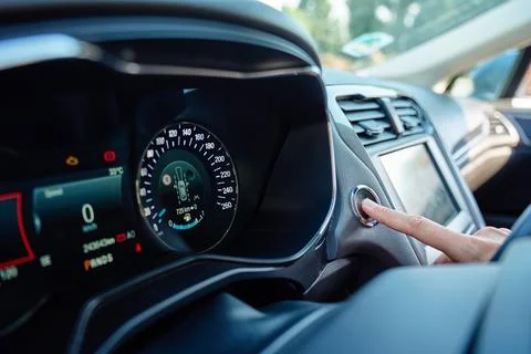 Driver pressing engine start button inside modern car Foto stock