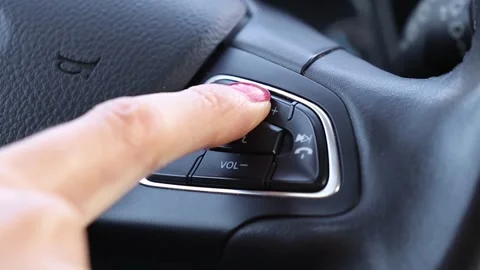 Driver pressing volume button of car radio on steering wheel of a car Stock Footage 242037487
