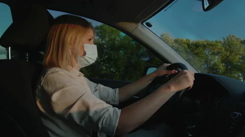Driver in protective mask drives behind the wheel of a car Stock Footage 136647963