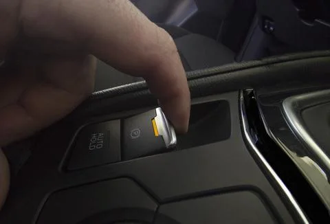 Driver pulling the electric parking brake of his car Stock Photos