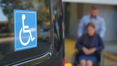 A driver pushing person with disability on a wheel chair 스톡 동영상 135101267