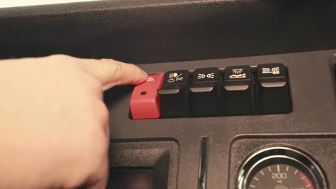 Driver pushing red hazard warning light button on dashboard Stock Footage 348178397