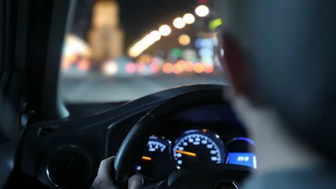 The driver puts his hand on the steering wheel of the car. night road and Stock Footage 133653947