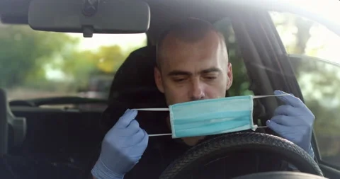 The driver puts on a mask in the car. Stock Footage 165132726