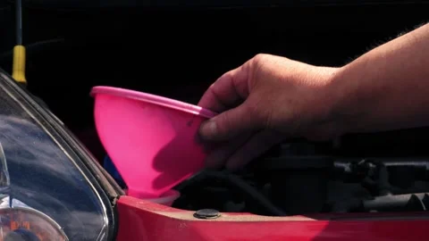 Driver putting funnel into windscreen wash tank in car Video stock 345910022