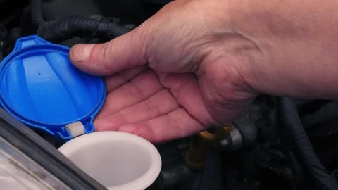 Driver putting funnel into windscreen wash tank in car 動画素材 346604785