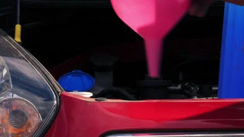 Driver putting funnel into windscreen wash tank in car 動画素材 346720440