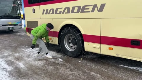 Driver putting winter chains on the bus wheel Stock Footage 234299091