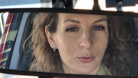 Driver reflection car mirror of a happy woman talking and smiling while sitting Stock Footage 322615356