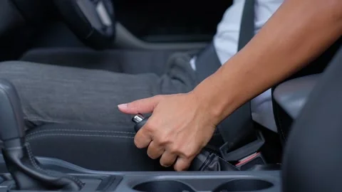 The driver releases the handbrake down to drive the car away. Stock Footage 133346787