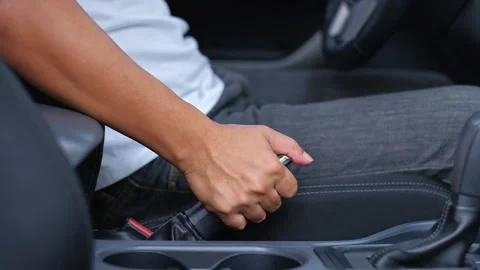 The driver releases the handbrake down to drive the car away. Stock Footage 144993005