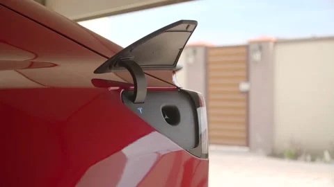 Driver removes the fast charger of her electric vehicle Stock Footage 231908106