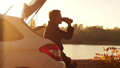 Driver resting by the river and drinking hot coffee in the fall Stock Footage 96686057