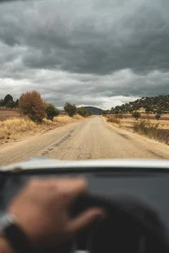 Driver s view through steering wheel on a cloudy country road Stock Photos