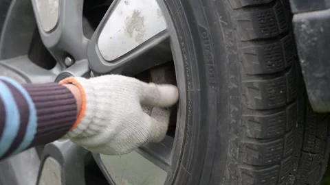 The driver is screwing on the wheel nipple cap of his car. Stock Footage 218813802