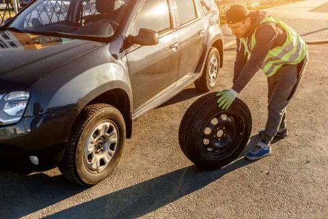 The driver should replace the old wheel with a spare. Man changing wheel after a Stock Photos