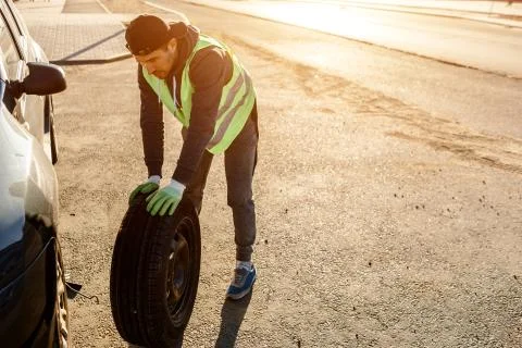 The driver should replace the old wheel with a spare. Man changing wheel after a Stock Photos