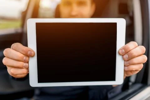 A driver shows a tablet pc screen close-up into the camera. Empty space for your Stock Photos