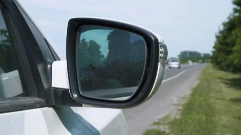 Driver sits behind the wheel of car parked on side of road with mobile phone Stock Footage 136954409