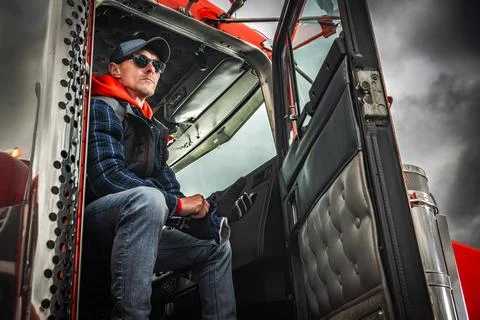 Driver sits in truck cab, preparing for journey on a cloudy day Stock Photos