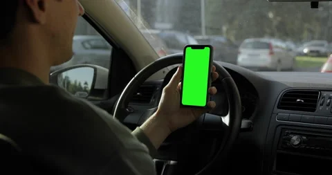 Driver sitting in the car and watching iPhone with green screen. Stock Footage 141203993